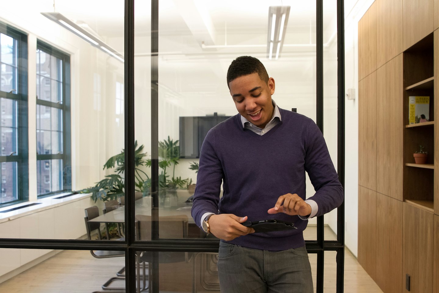 Man smiles using a tablet in a modern office.